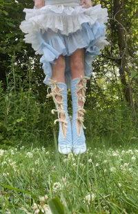 a little girl in a blue dress standing in the grass