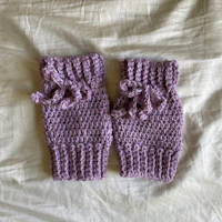 a pair of purple crocheted fingerless mitts on a bed
