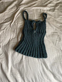 a green crocheted top on a bed