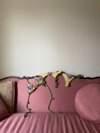 a pink couch with a crocheted flower on it