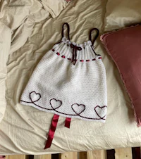 a white crocheted dress with red hearts on a bed