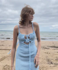a woman wearing a blue knitted dress on the beach