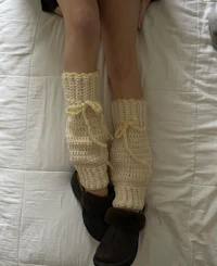 a woman wearing a pair of crocheted leg warmers on a bed