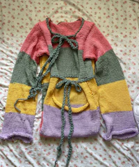a colorful knit sweater on a bed