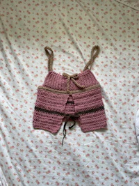 a pink and brown crocheted outfit on a bed