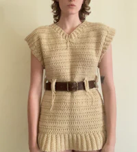 a woman wearing a crocheted dress with a belt