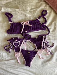 two purple crocheted bikinis laying on a bed