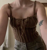 a woman is taking a selfie in a brown knitted top