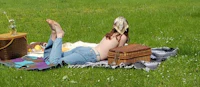 a woman laying on the grass with a picnic basket