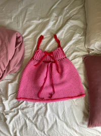 a pink knitted dress laying on a bed