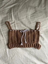 a brown crocheted top on a bed