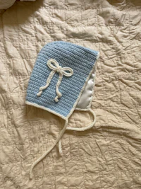 a blue and white knitted hat on a bed