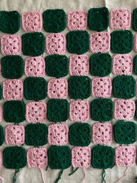 pink and green crocheted squares on a table