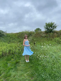 a girl in a blue dress standing in a field