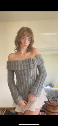 a woman is posing in a room wearing a sweater