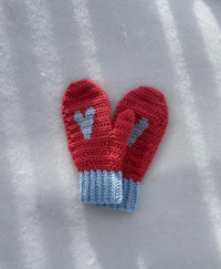a pair of red and blue crocheted mittens in the snow