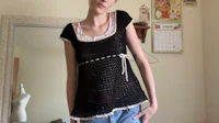 a woman wearing a black crocheted top and jeans