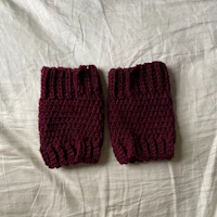 a pair of burgundy knitted wrist warmers on a bed